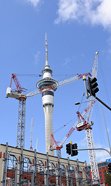 Construction site filled with cranes with Auckland’s Sky Tower in the background.