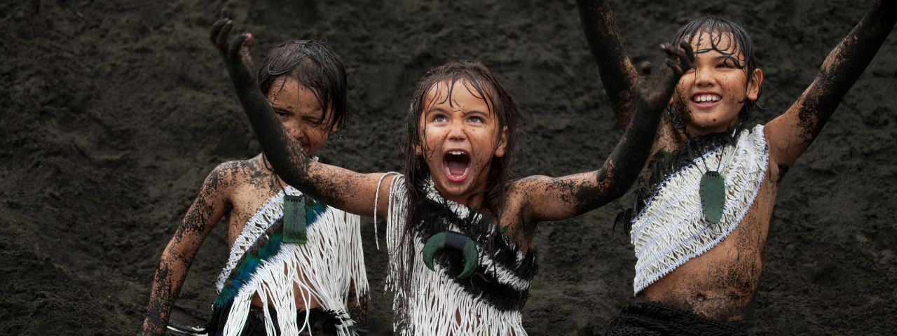 Three Tamariki (children) playing in sand with pounamu 