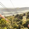 Two people on a zipline over treetops with EcoZip Adventures