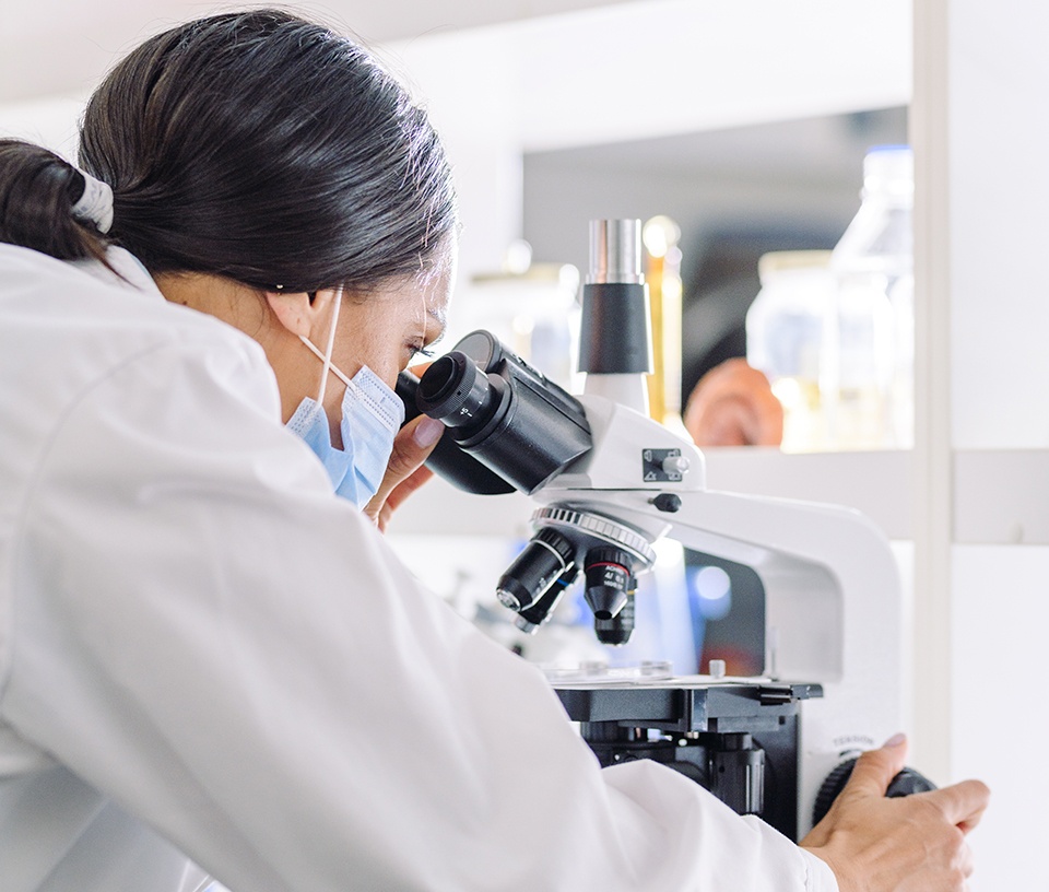 Female lab technician looking through a microscope