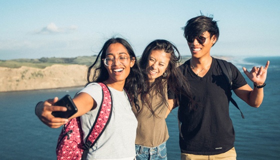 Group of students taking selfies on a cliff top